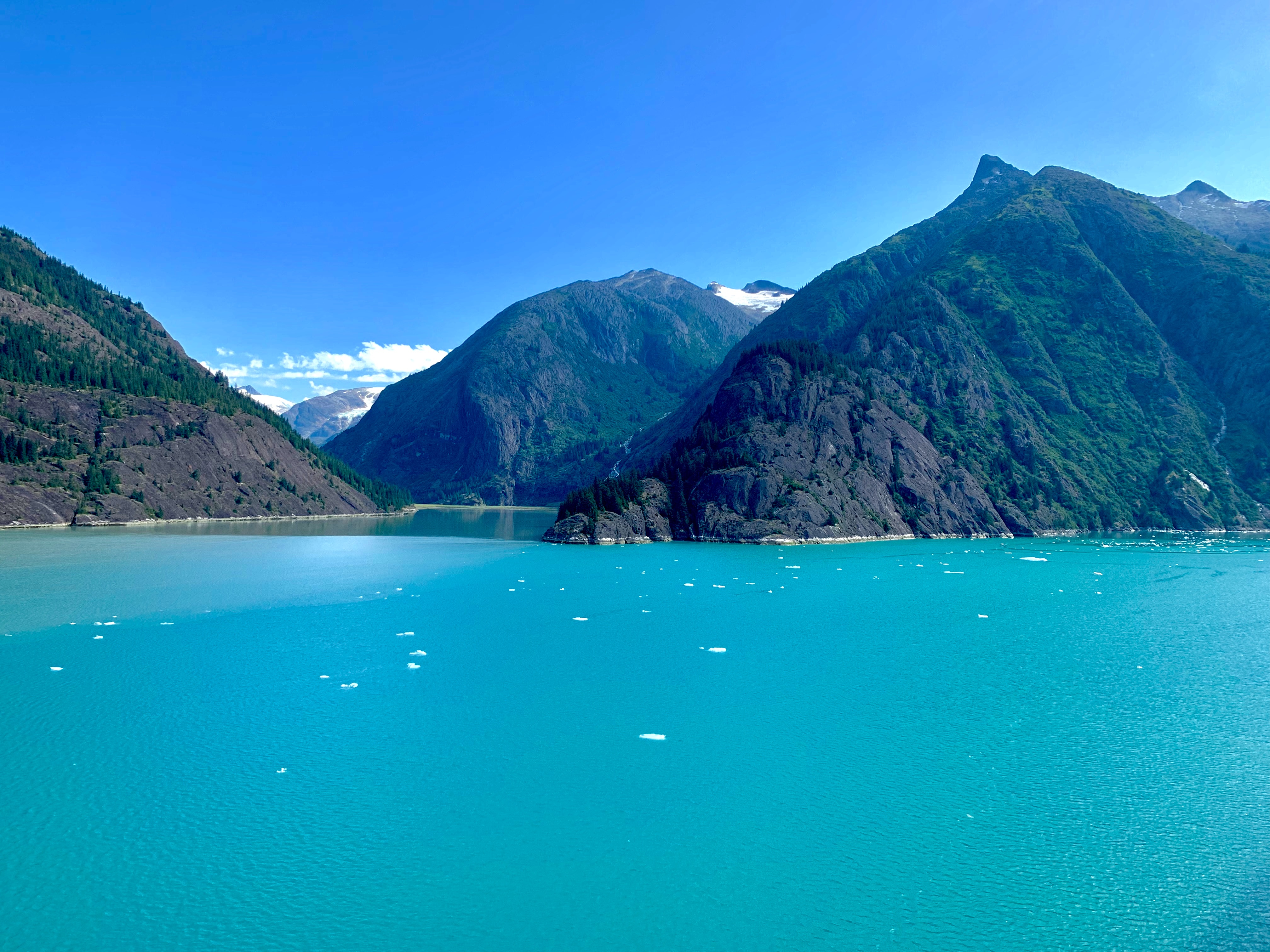 Bright glacial blue waters surrounding the rocky coast with clear skies 